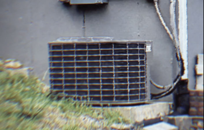 old ac condenser unit installed outside a gray-colored home