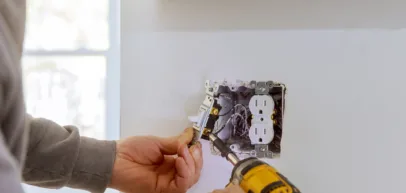 Electrician performing electrical repair service on outlet or electrical panel